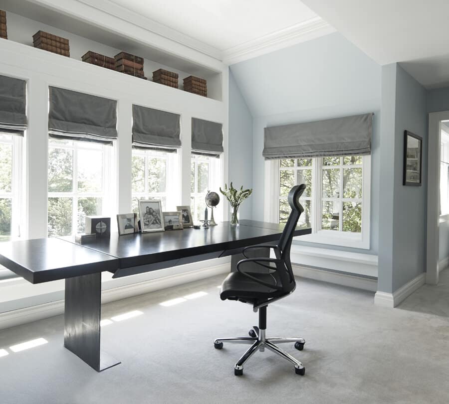 Modern home office with large windows and black furniture.