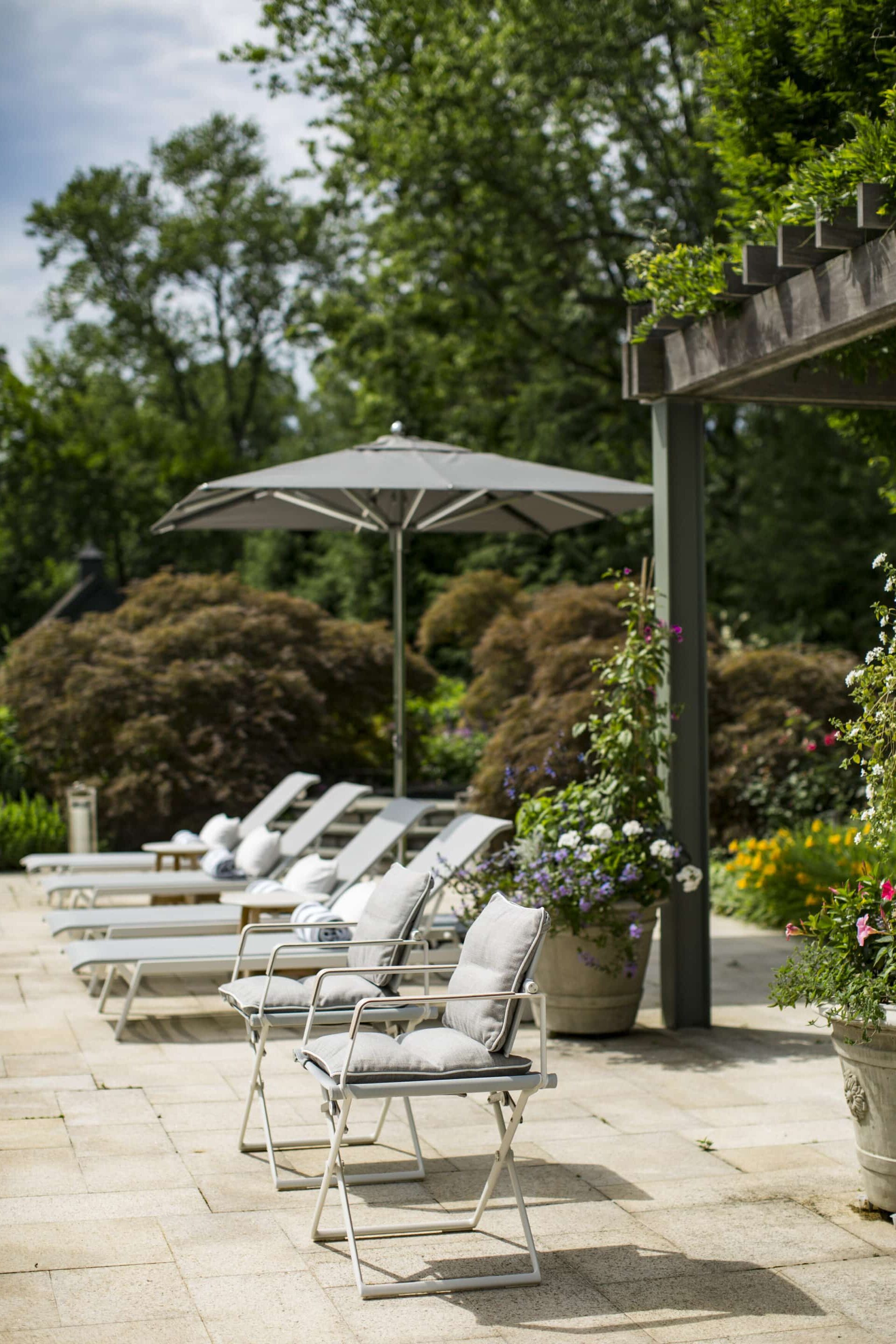 Sunny garden patio with lounge chairs and umbrella.