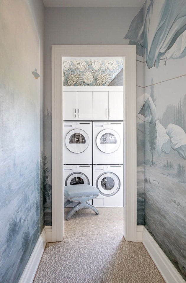 Laundry room with stacked washer and dryer, decorative mural walls.
