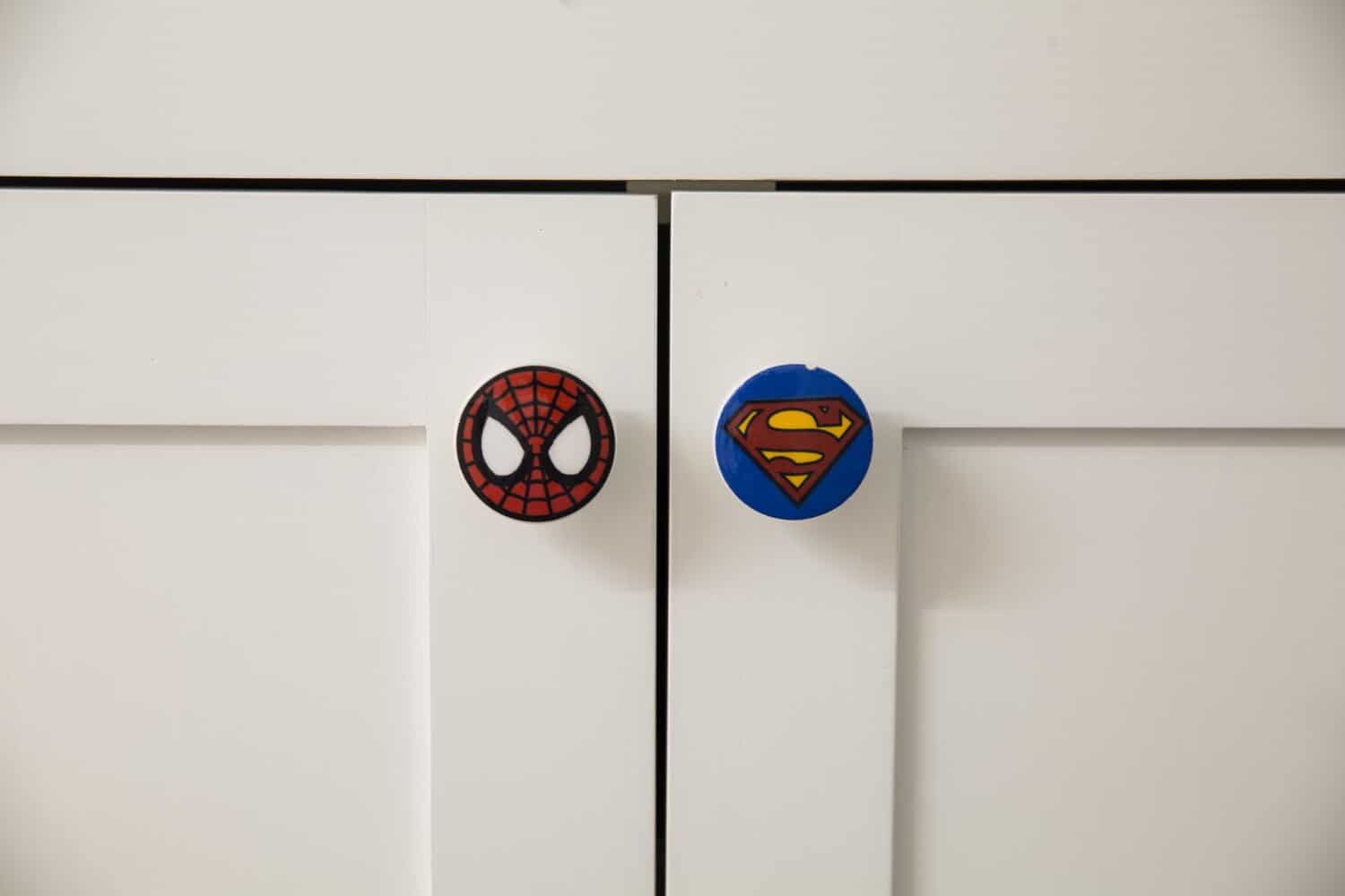 Spider-Man and Superman knobs on white cabinet