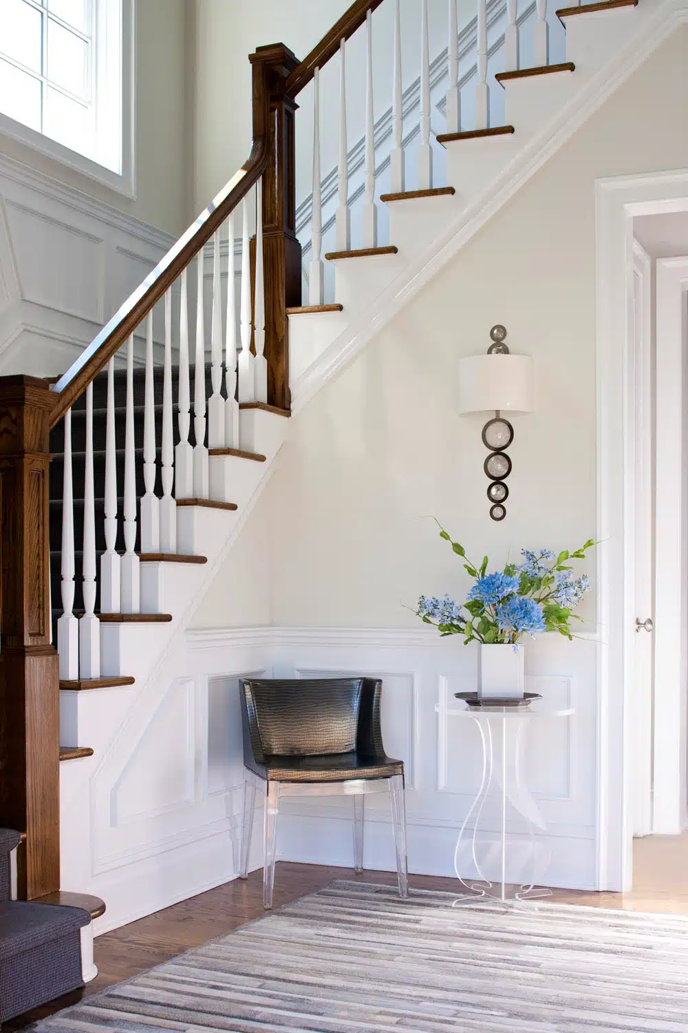 Elegant staircase with chair and decorative vase in hallway.