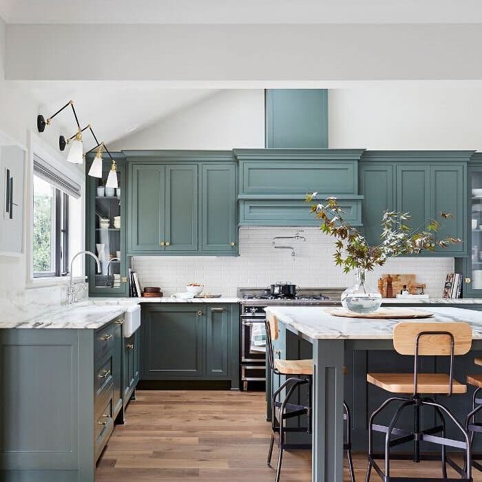 Modern kitchen with teal cabinets and marble countertops.