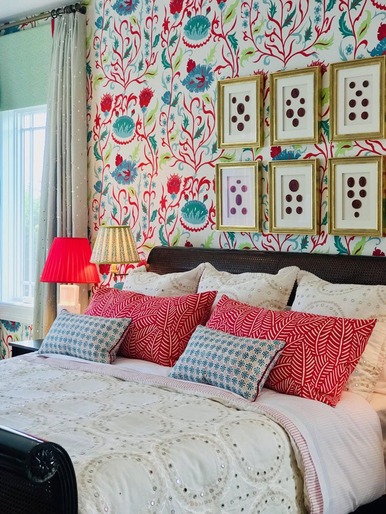 Colorful eclectic bedroom interior with patterned wallpaper and bedding.