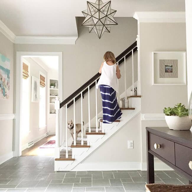 Woman descending stairs in a bright home interior.